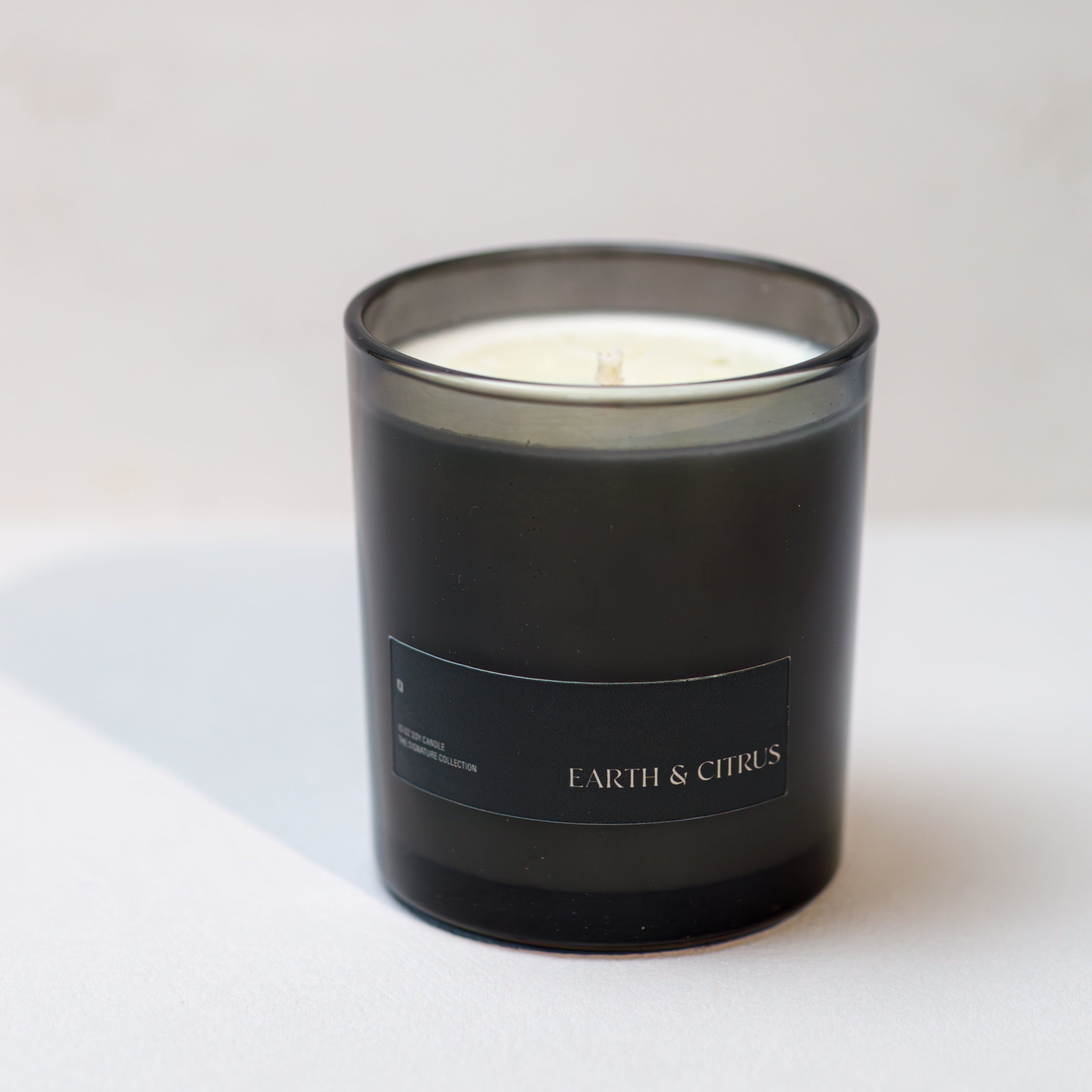 Black candle with 'Earth & Cirrus' branding on a white background