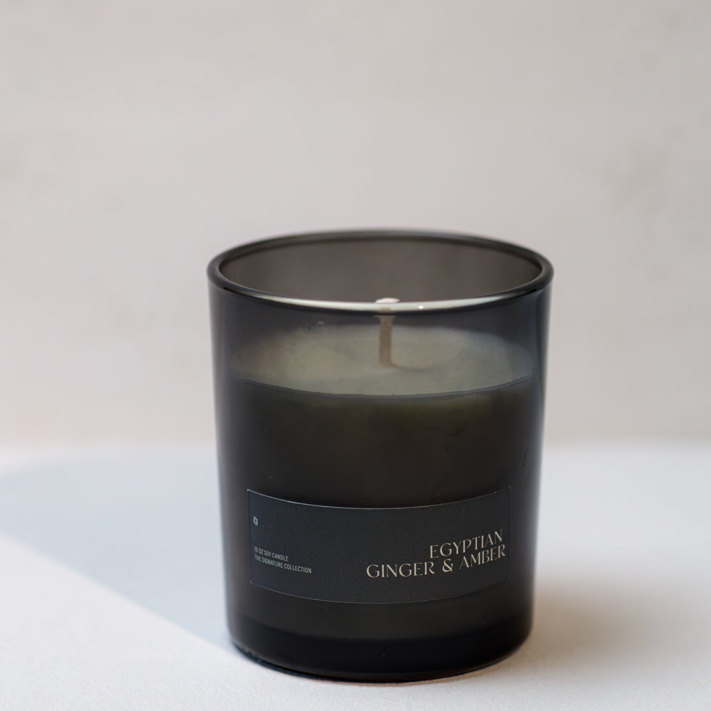 Black candle with 'Egyptian Ginger & Amber' label on a white background