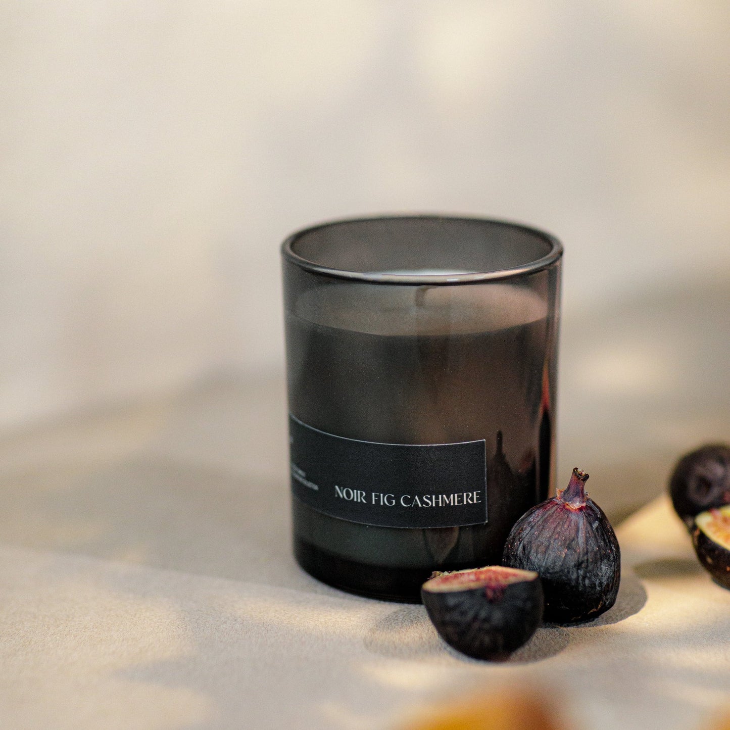 Black candle labeled 'Nobile Fig Cashmere' with figs on a light surface